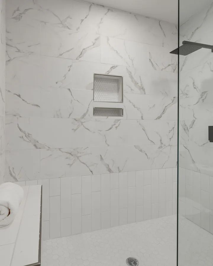 White marble-look tile walk-in shower with glass panel and bench