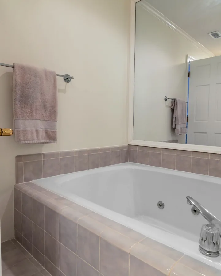 White jetted tub in mauve tile surround, seen through an open door